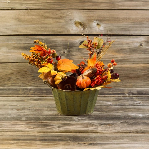 Herbstliche Tischdeko mit Naturmaterialien in einem rustikalen grünen Blumentopf.
